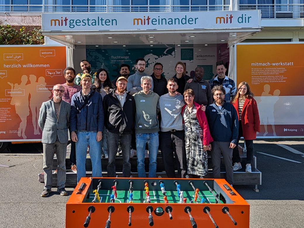 Eine Gruppe von Menschen steht vor dem Mitmachmobil des Kolping-Netzwerkes für Geflüchtete.